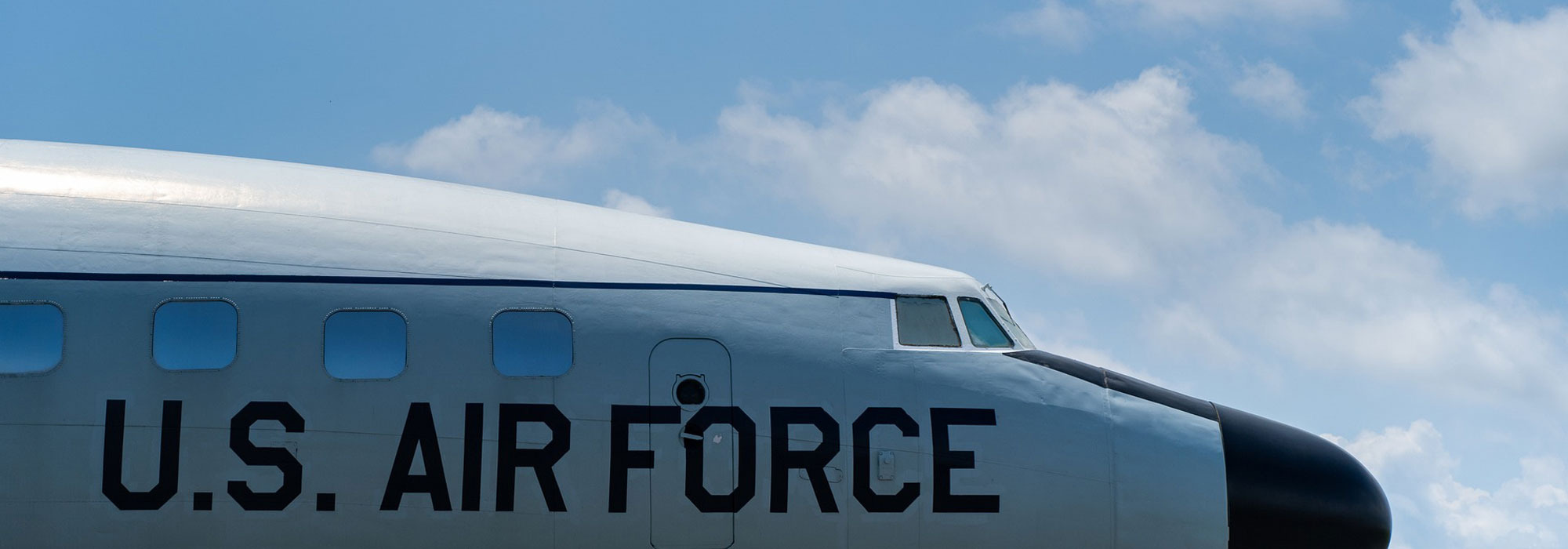 Nahaufnahme eines Flugzeugs der U.S. Air Force mit sichtbarem Schriftzug vor blauem Himmel mit Wolken.