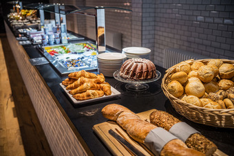 Buffettisch mit Broten, Croissants, Gugelhupf und Tellern, alles appetitlich angerichtet.