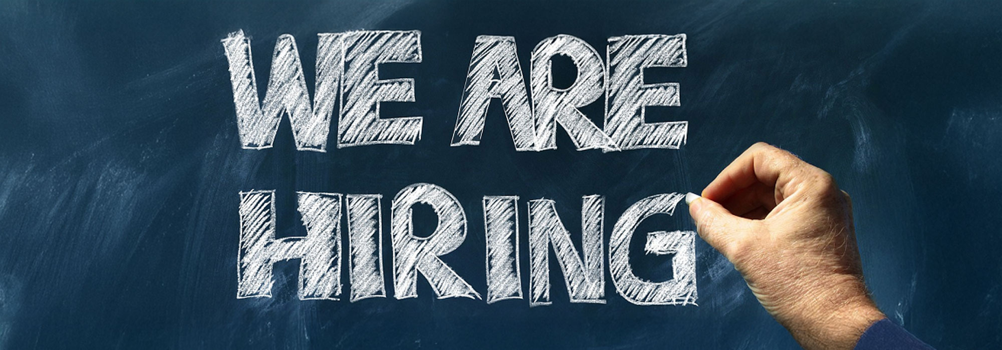 Schriftzug „WE ARE HIRING“ auf dunkelblauem Hintergrund als Hinweis auf offene Stellen oder Jobangebote.